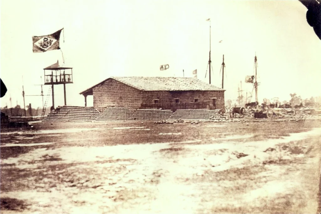 Fotografía del puerto de Humaitá con una construcción, una bandera y mástiles de barcos al fondo.